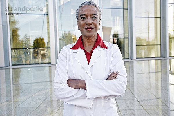 Porträt eines lächelnden afroamerikanischen Arztes im Freien vor einem Krankenhaus