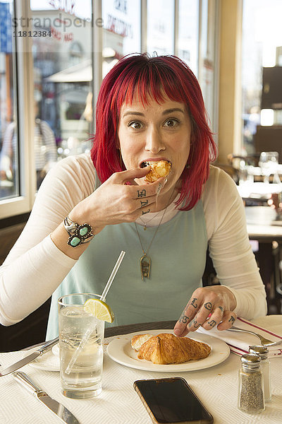 Kaukasische Frau isst Croissant im Restaurant