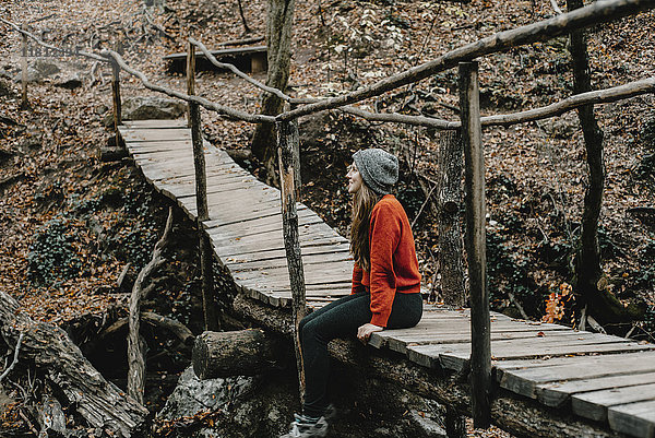 Kaukasische Frau sitzt auf einem Steg im Wald