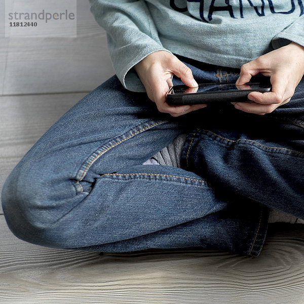 Nahaufnahme eines kaukasischen Jungen  der mit einem Mobiltelefon spielt