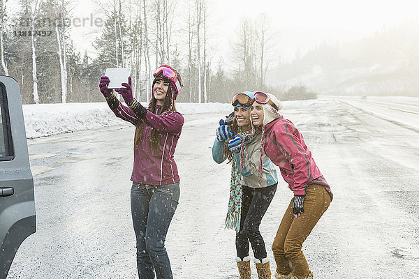 Frauen posieren für Handy-Selfie im Winter mit digitalen Tablette