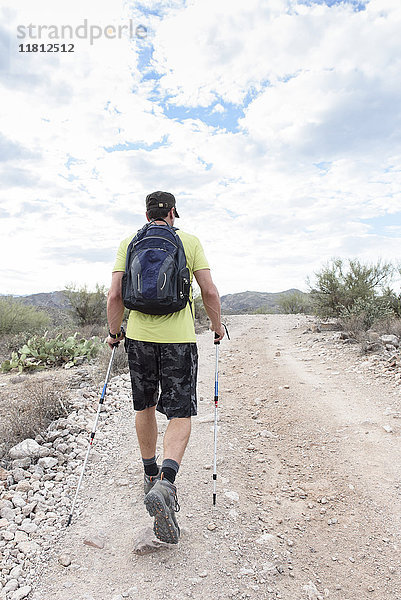 Hispanischer Mann wandert auf felsigem Pfad in der Wüste