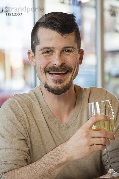 Porträt eines kaukasischen Mannes  der Weißwein trinkt