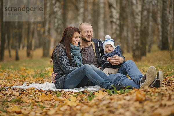 Ehepaar aus dem Nahen Osten sitzt mit ihrem kleinen Sohn im Herbst im Park