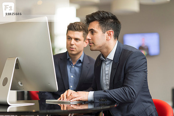 Zwei Geschäftsleute schauen auf Büro-Desktop-Computer