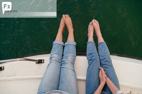 Zwei Frauen  entspannen sich auf dem Boot  Füße über Bootskante  barfuß  Blick nach oben