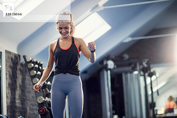 Fröhliche junge Frau trainiert  schaut im Fitnessstudio nach unten