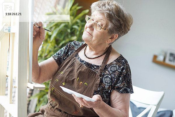 Ältere erwachsene Frau malt auf Staffelei