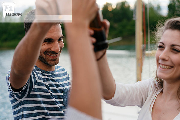 Drei Freunde am See  Bierflaschen haltend  einen Toast aussprechend