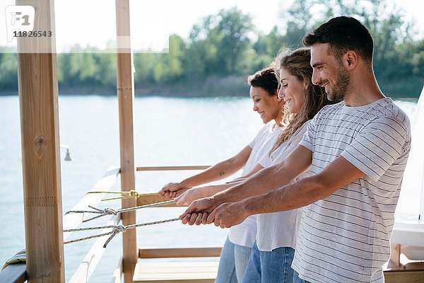 Drei Freunde auf der Mole  an Seilen mit nautischen Knoten ziehend