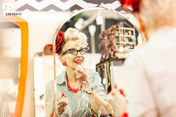 Spiegelbild einer schrulligen Vintage-Frau  die Lippenstift in Antiquitäten- und Vintage-Läden aufträgt