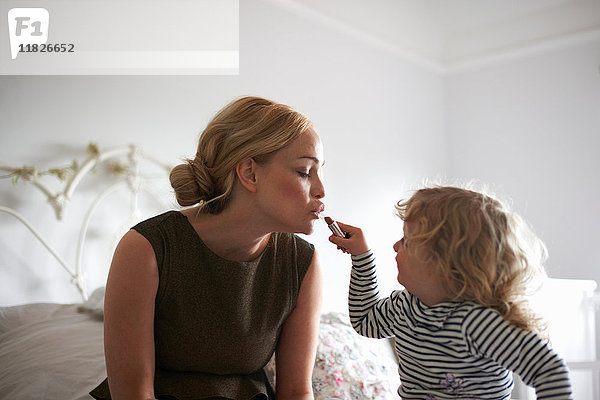 Tochter hilft der Mutter beim Auftragen von Lippenstift