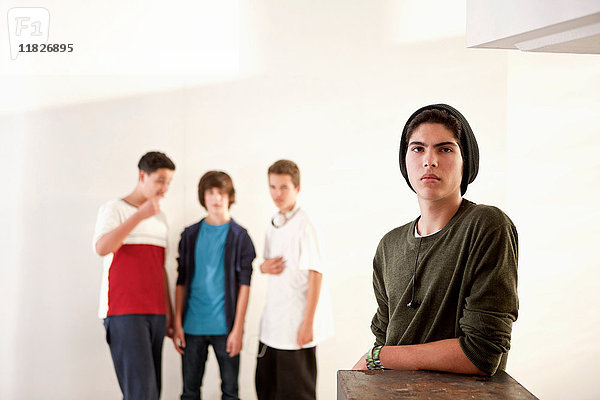Teenager  der sich mit Freunden im Hintergrund an eine Kiste lehnt
