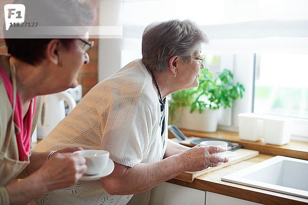 Ältere erwachsene Frauen  die Kaffee trinken und aus dem Fenster schauen