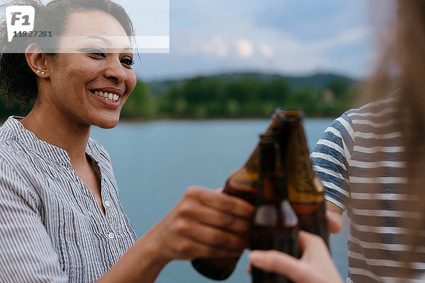 Drei Freunde am See  Bierflaschen haltend  einen Toast aussprechend