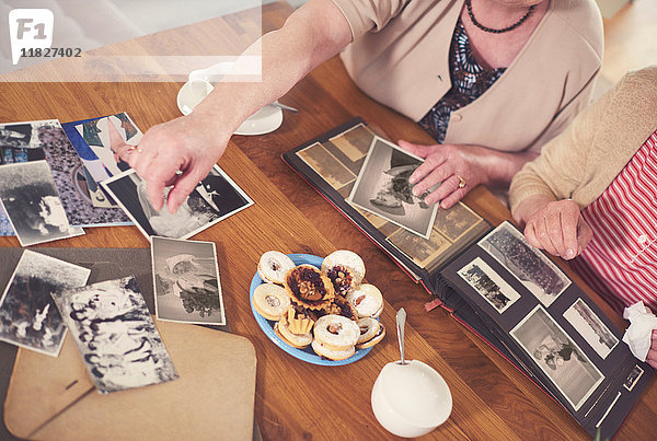 Draufsicht von zwei älteren Frauen  die sich alte Fotos bei Tisch anschauen