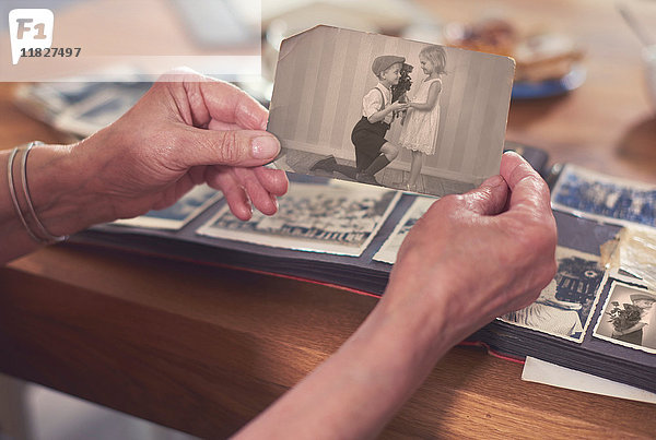Hände einer älteren Frau  die ein altes Foto eines Jungen und eines Mädchens hält
