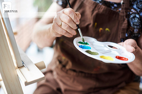 Frau hält Palette mit Pinsel und Farben