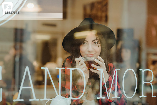 Porträt einer jungen Frau im Cafe sitzend  Blick durchs Fenster