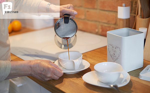 Ältere erwachsene Frau gießt Kaffee in Tassen