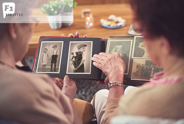 Über-Schulter-Ansicht von zwei älteren Frauen beim Betrachten eines alten Fotoalbums