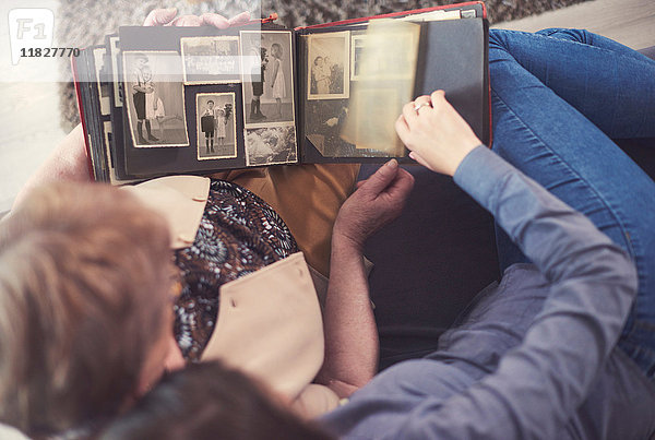 Draufsicht einer jungen Frau auf dem Sofa mit Großmutter beim Betrachten des Fotoalbums