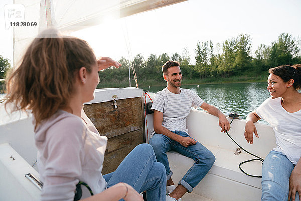 Drei Freunde entspannen sich auf einem Segelboot auf dem See