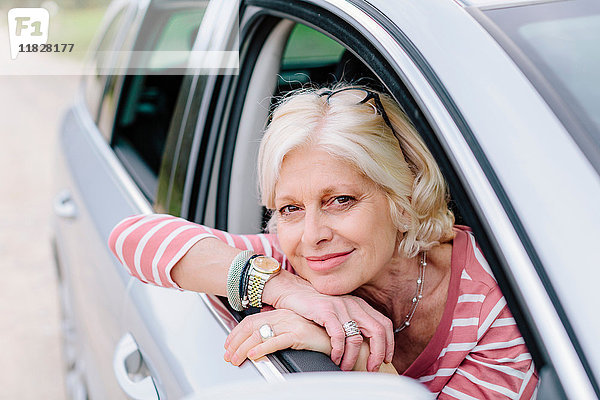 Porträt einer reifen Frau  die am Straßenrand aus dem Autofenster schaut