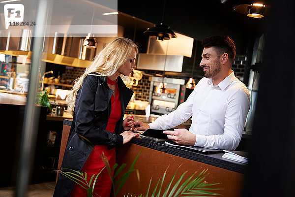 Kellner berührt die Hand einer jungen Frau an der Restauranttheke