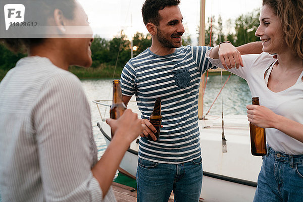 Drei Freunde auf der Mole  neben dem Boot  entspannen sich  halten Bierflaschen