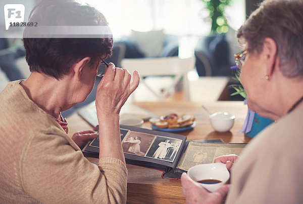 Über-Schulter-Ansicht zweier älterer Frauen beim Betrachten des Fotoalbums auf dem Tisch