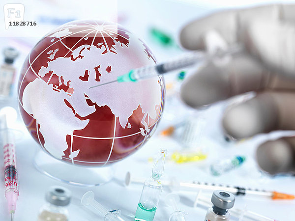 Arzt injiziert dem Globus Impfstoff  um eine Heilung für eine globale Pandemie zu veranschaulichen