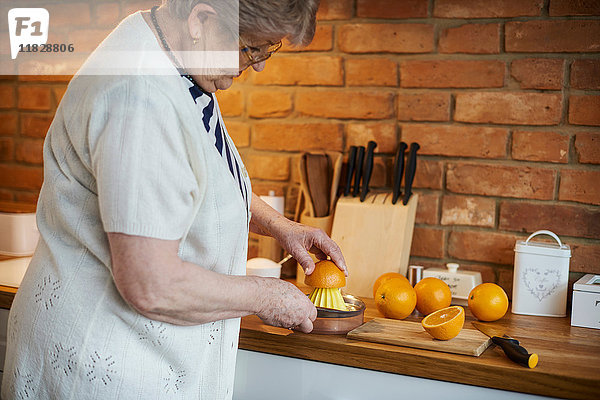 Ältere erwachsene Frau beim Auspressen von Orangen