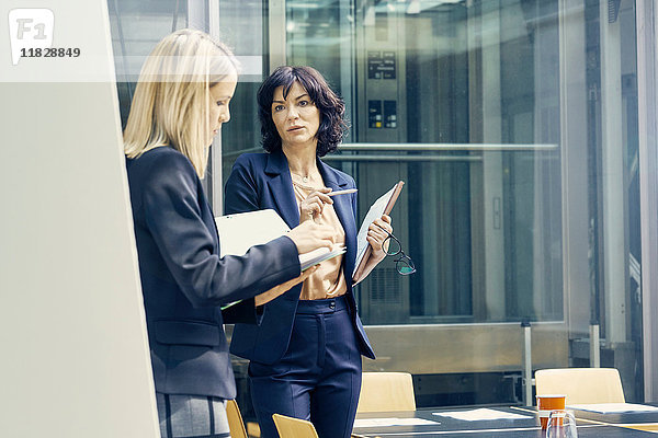 Zwei Geschäftsfrauen diskutieren im Großraumbüro