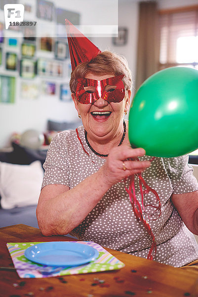 Ältere Frau winkt mit Luftballons bei Geburtstagsfeier