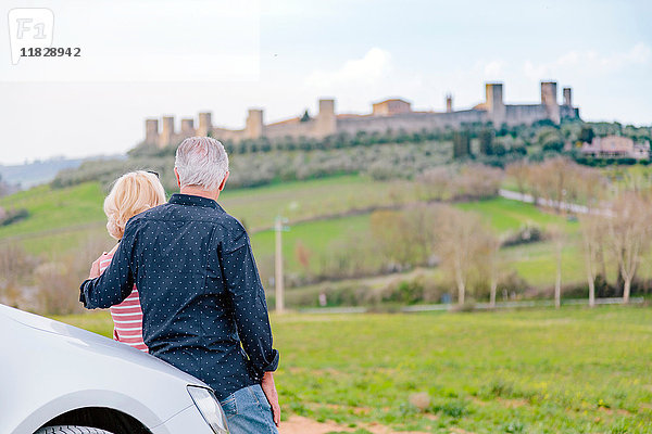 Rückansicht eines Touristenpaares mit Blick auf eine Festung in der Landschaft  Siena  Toskana  Italien