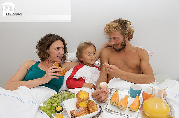 junge Familie beim Frühstück im Bett