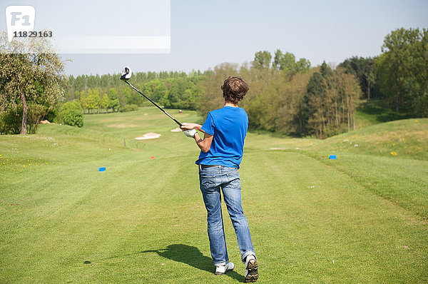 Junge schwingt den Schläger auf dem Golfplatz