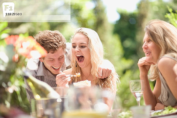 Familie lacht bei Tisch im Freien