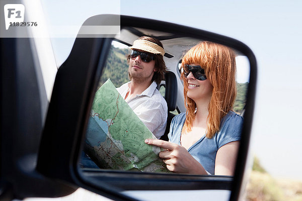 Paar mit Karte im Autospiegel
