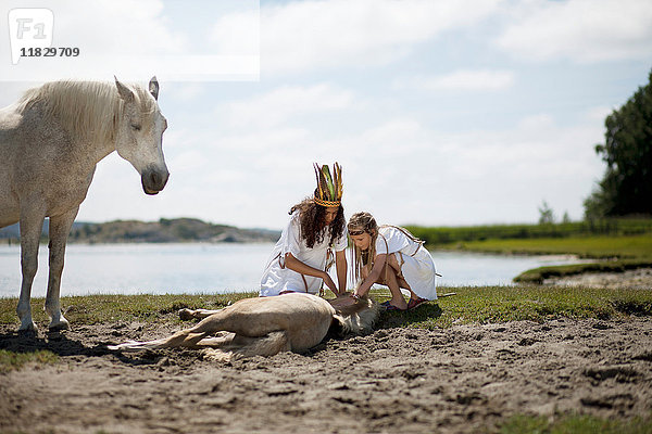 Mädchen streicheln Pferd am Sandstrand