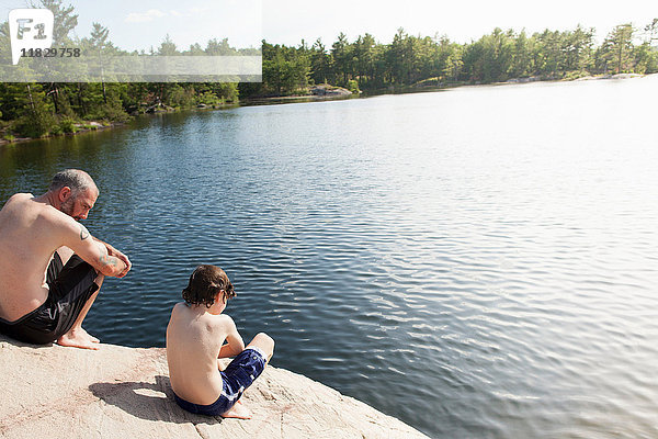 Vater und Sohn sitzen am stillen See