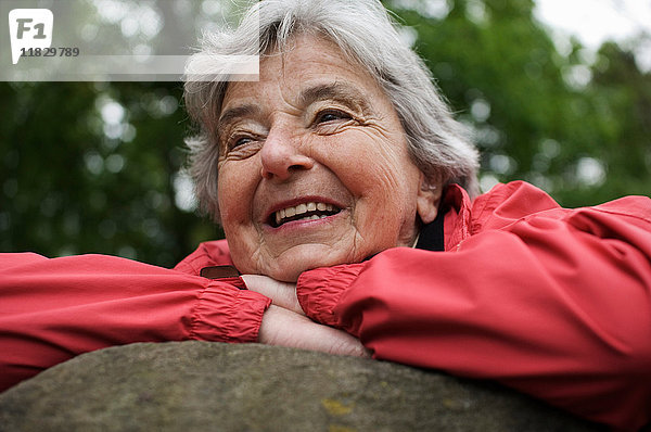 Ältere Frau ruht auf Fels im Park