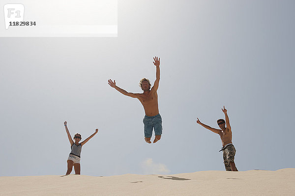 Mann springt über eine große Sanddüne