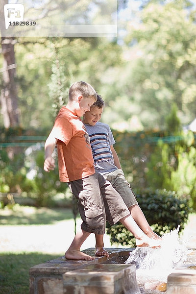 Jungen spielen im Springbrunnen