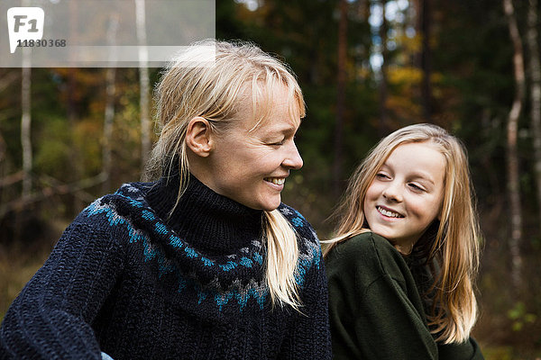 Mutter und Tochter lächelnd im Wald