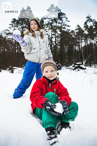 Kinder machen Schneebälle im Schnee