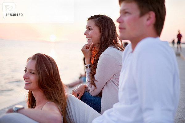 Lächelnde Menschen sitzen auf dem Pier im Freien