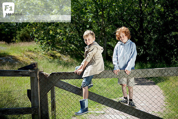 Kinder klettern auf Holzzaun im Freien