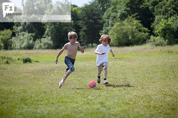 Kinder spielen Fussball auf einem Rasenplatz